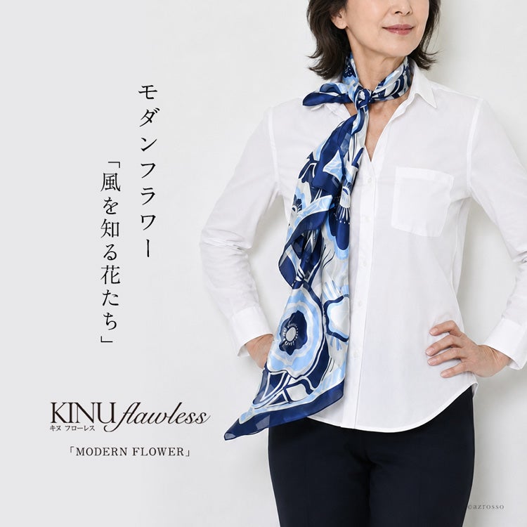 白シャツの首元にネイビーの花柄シルクスカーフを結び、片側を長く垂らした着用例。キヌフローレス「モダンフラワー」