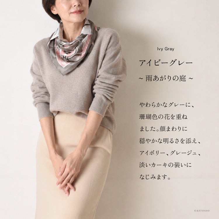 グレージュのニットに、グレーと淡いピンクの花柄シルクスカーフを胸元にふんわり巻いた着用例。アイビーグレー