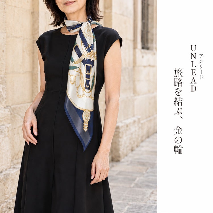 黒のワンピースにネイビーの馬具柄シルクスカーフを長く垂らした、上品なお出かけコーデ。日本製の大判90cm「アンリード」