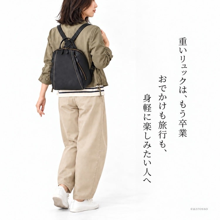 黒の小さめレザーリュックを背負った小柄な女性。淡いジャケットと白のパンツのお出かけコーデ。