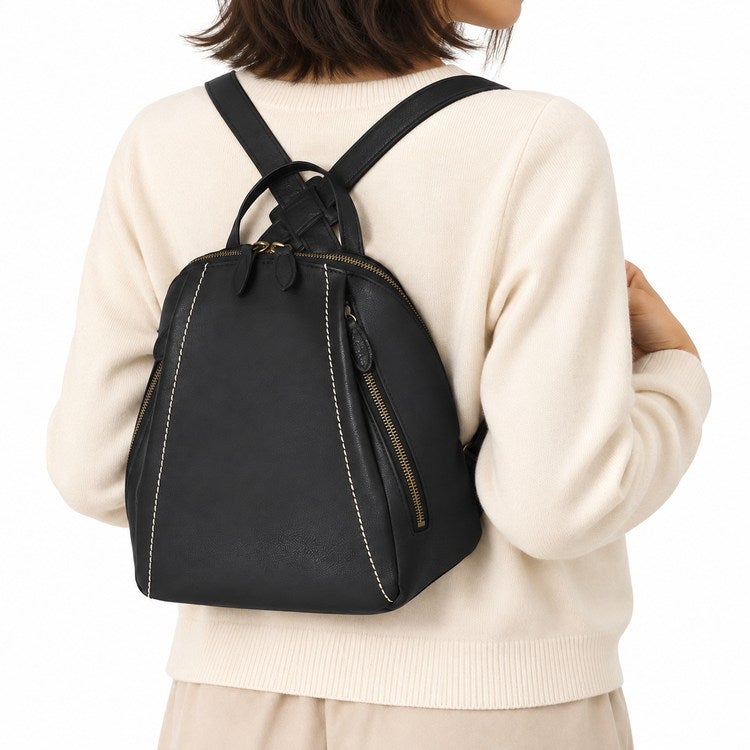 ブラックの日本製本革ミニリュックを淡いジャケットに合わせた女性の後ろ姿。