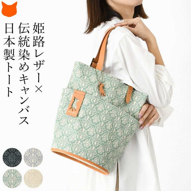 上品なダマスク柄にさりげない猫モチーフを施した日本製キャンバストートバッグを肩掛けして使用する女性モデル。縦型A4対応の帆布×姫路レザーを使用した軽量バッグ。