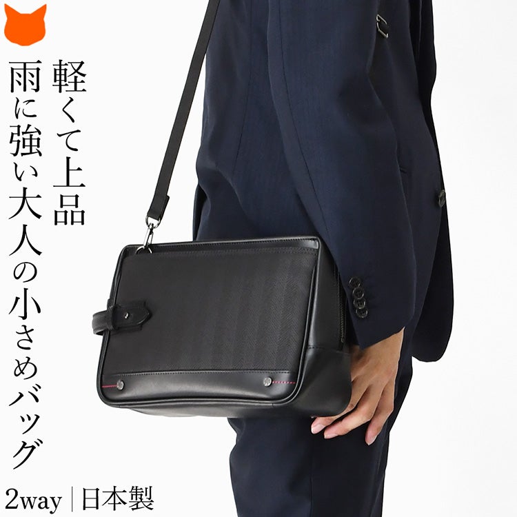 ウノフク（UNOFUKU）謹製、豊岡鞄のメンズ2WAYミニショルダーバッグを肩掛けするスーツスタイルの男性。軽量で防水性の高いナイロンを使用した日本製セカンドバッグ。